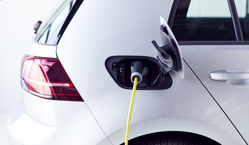an electric car is plugged in to charge in preparation for its MOT.