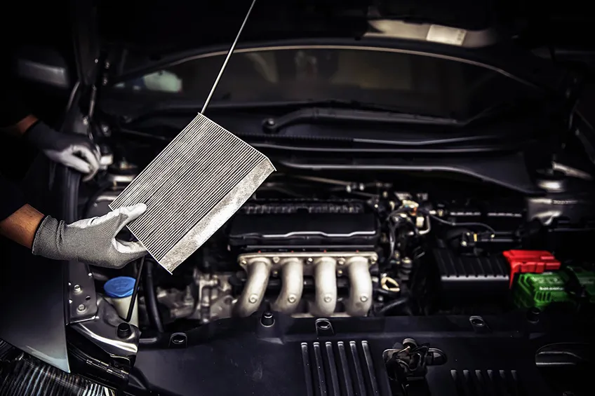 A car mechanic inspects an air conditioning system filter for dust and debris.