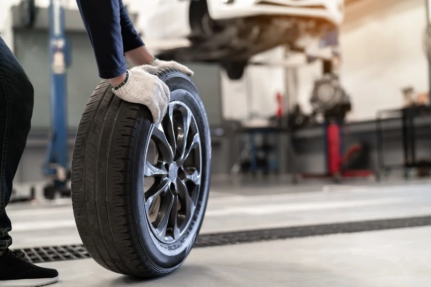 A mechanic rolls a worn down tyre across the floor of an autocentre.