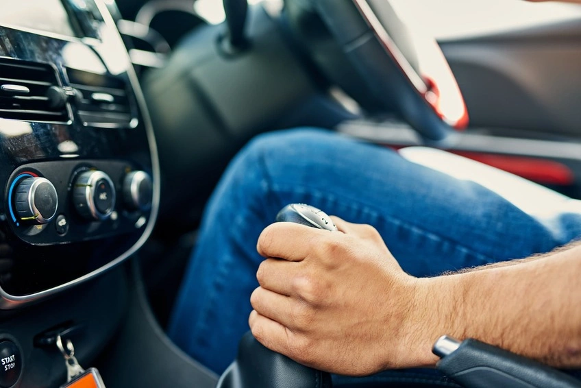 A close up of a driver gripping the gearstick with his left hand while changing gear.